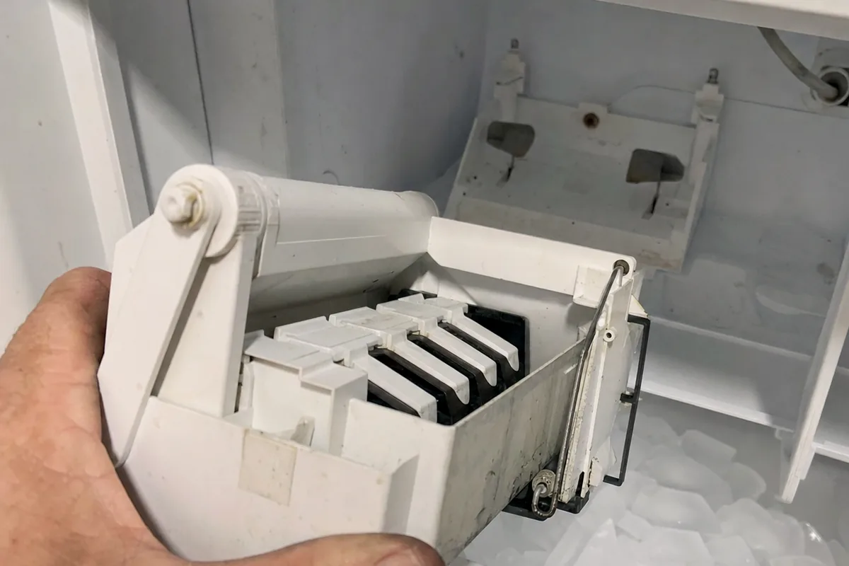 Tight view of an ice maker mould and its ejector fingers, half-released cubes still sitting in the tray